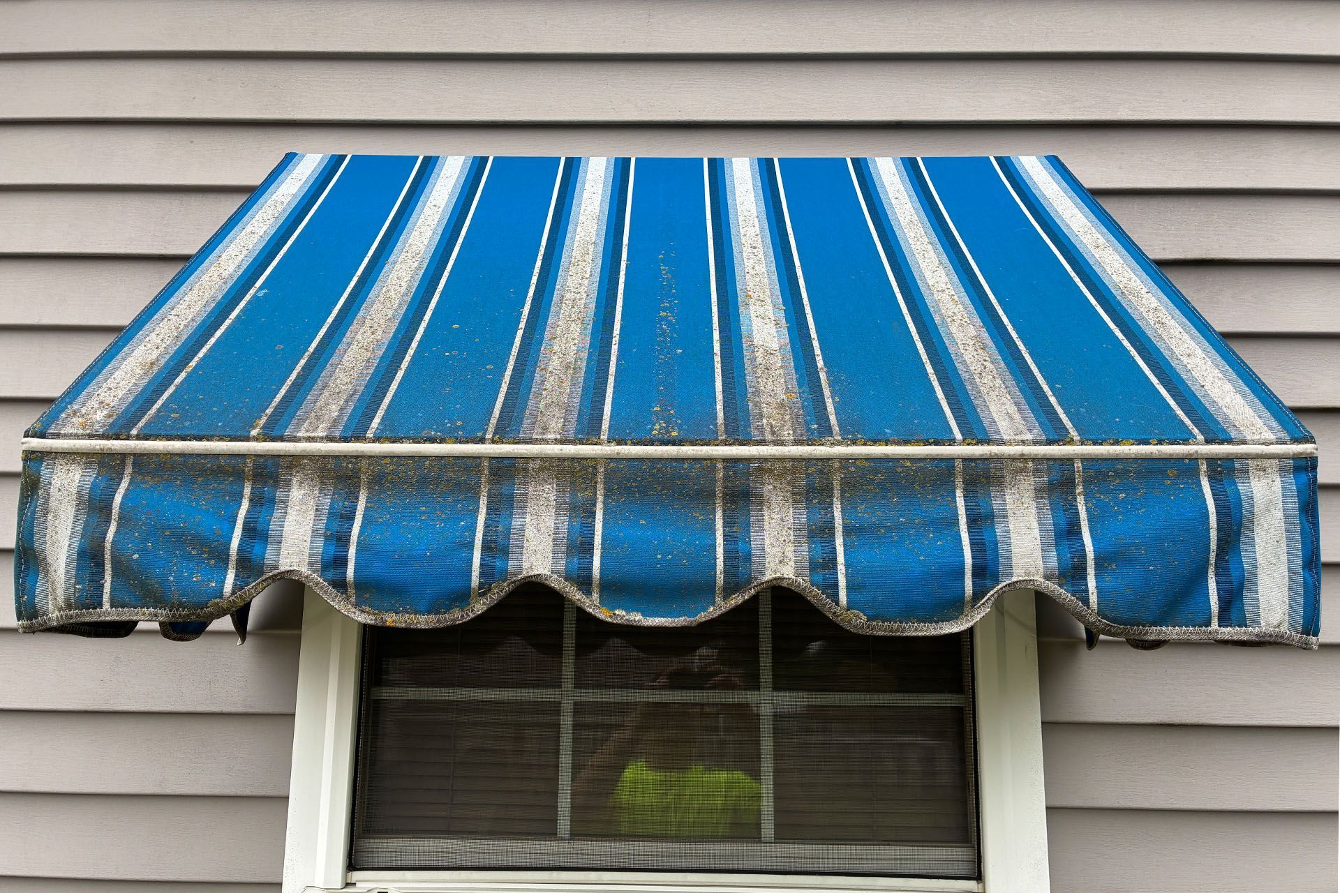 Blue striped awning over a window on a house exterior