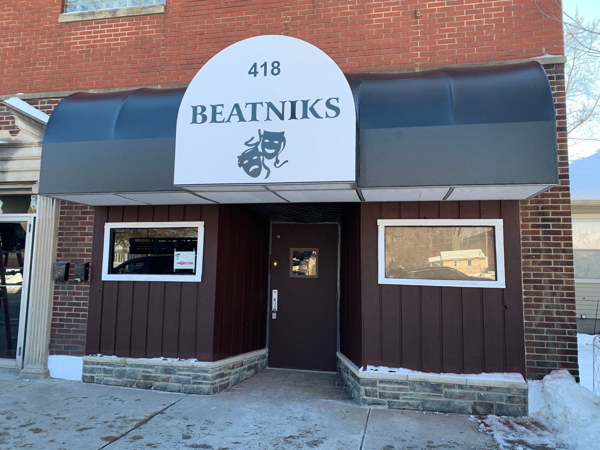 Storefront with sign reading “418 BEATNIKS,” dark awning, and snow on the ground