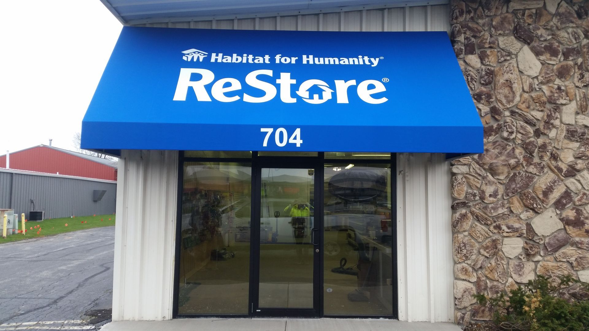 Habitat for Humanity ReStore storefront with blue awning and glass entrance, number 704