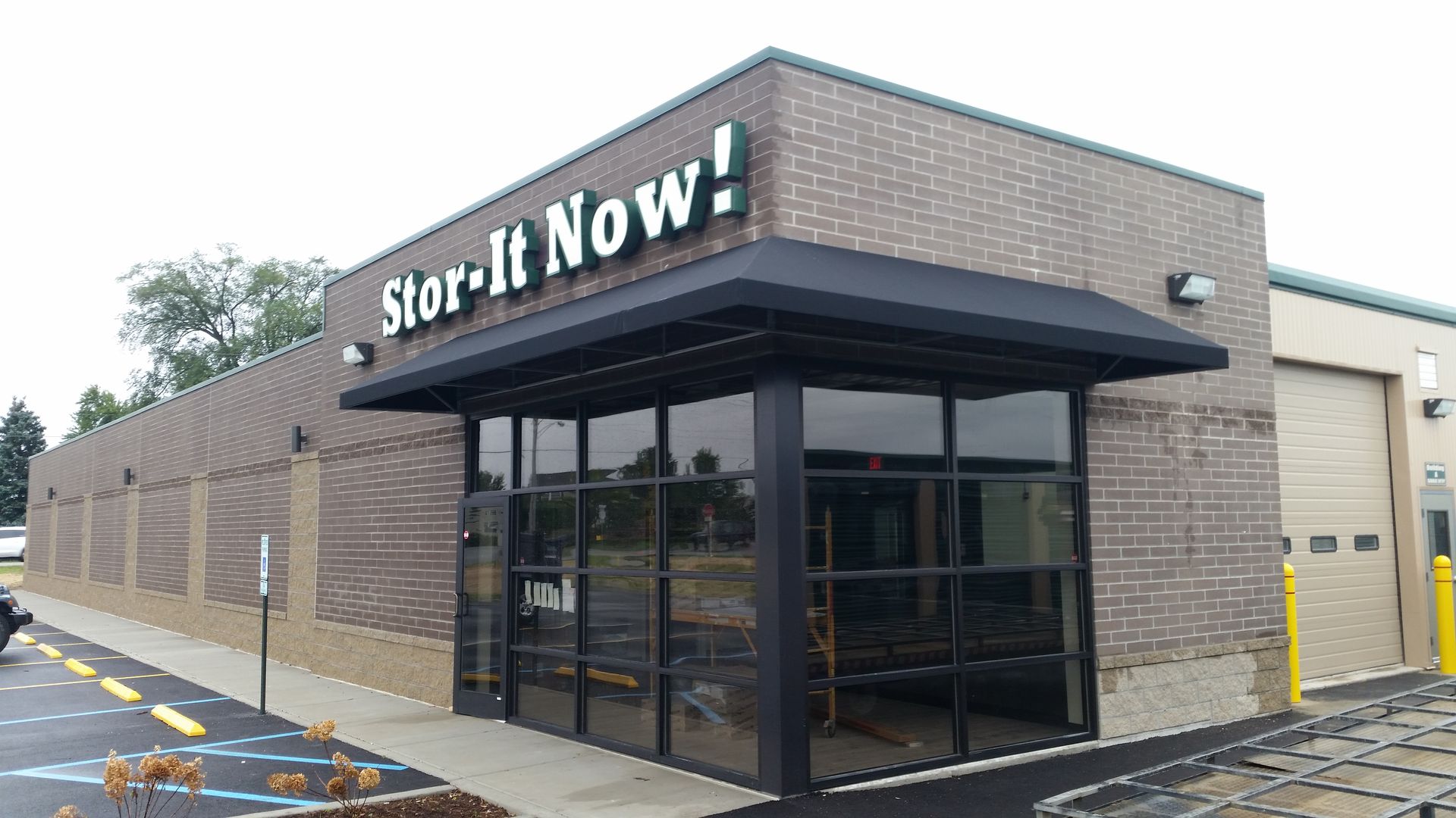 Store It Now self-storage building with brick exterior and black awning at a street corner