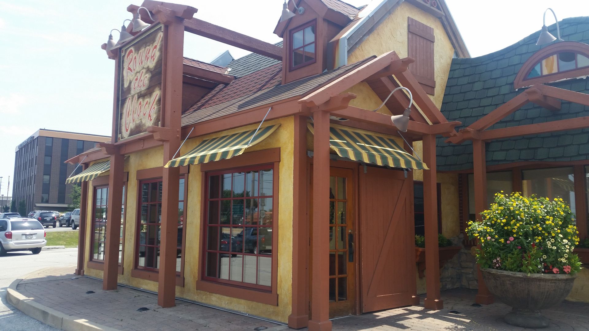 Small wooden storefront with green-striped awning and red roof on a sunny street corner