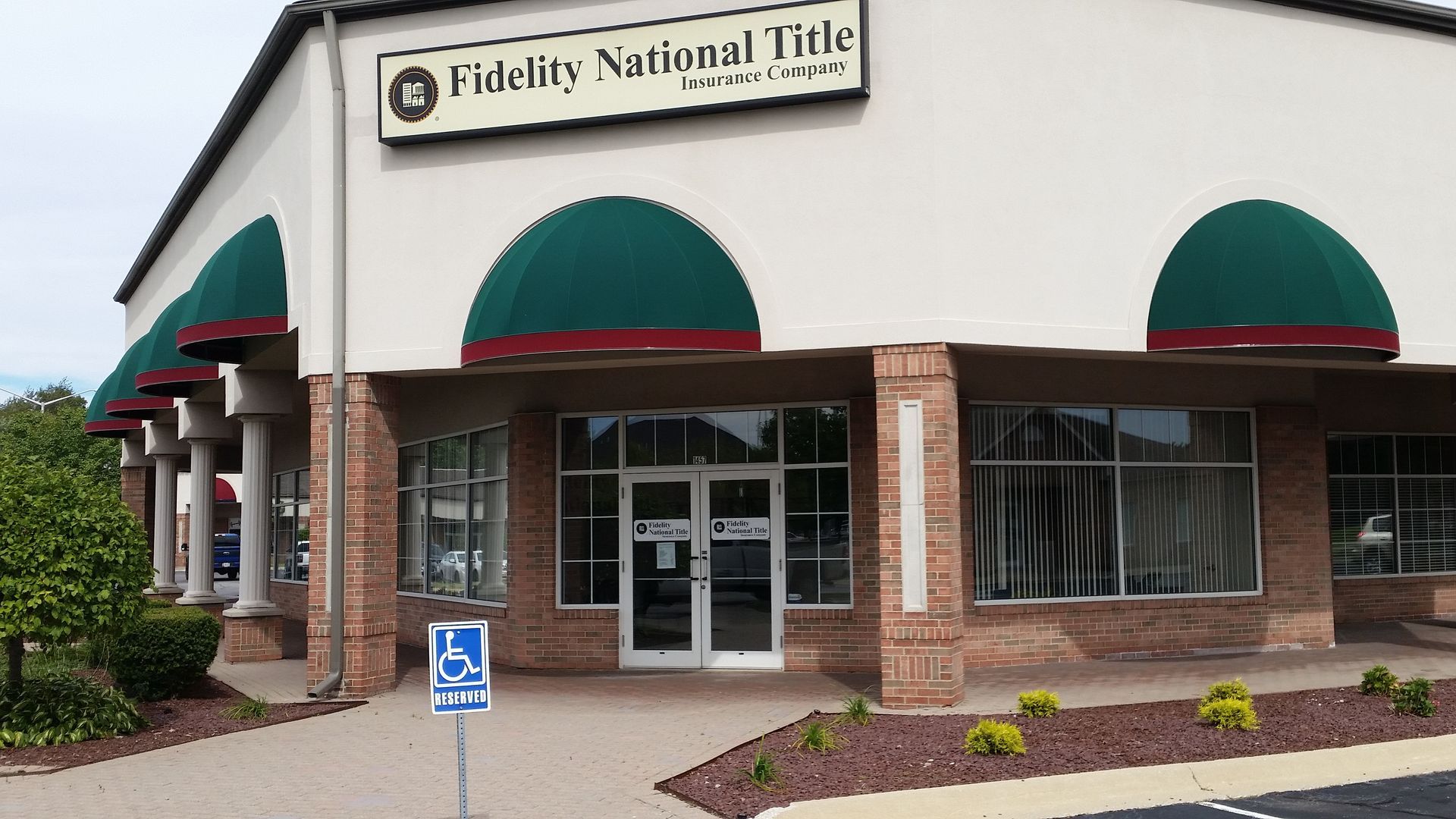 Fidelity National Title office exterior with green awnings and brick columns at the entrance