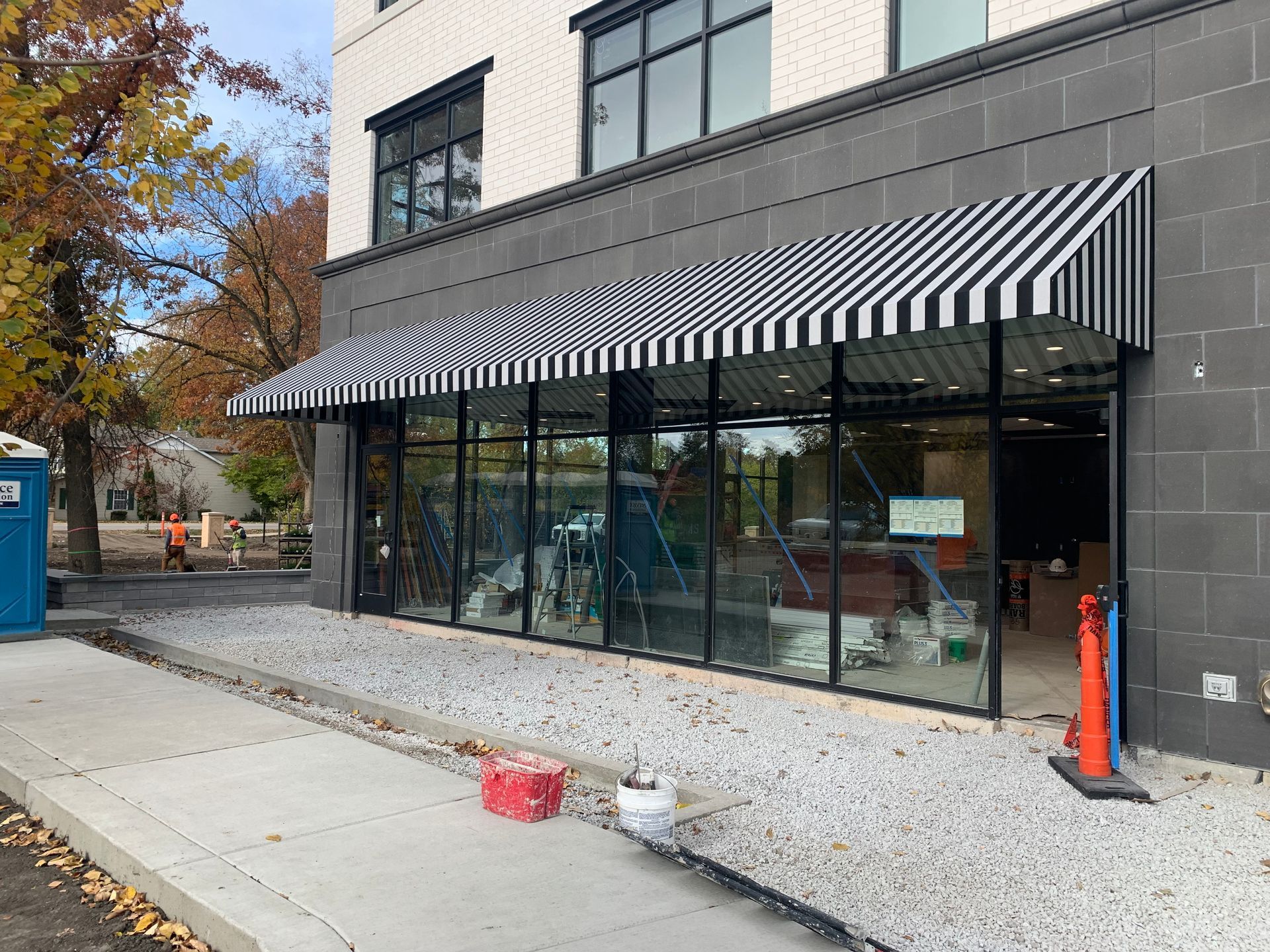 Storefront with black-and-white striped awning and large glass windows on a city sidewalk.