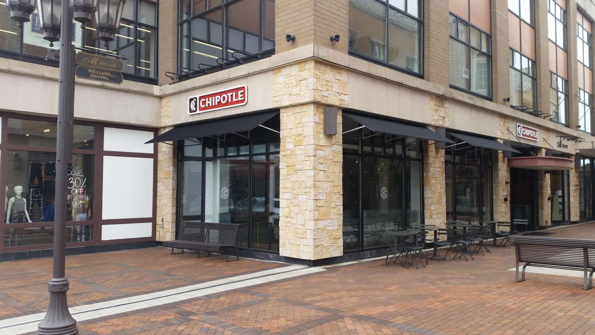 Modern storefront with stone columns and glass windows in a paved outdoor plaza.