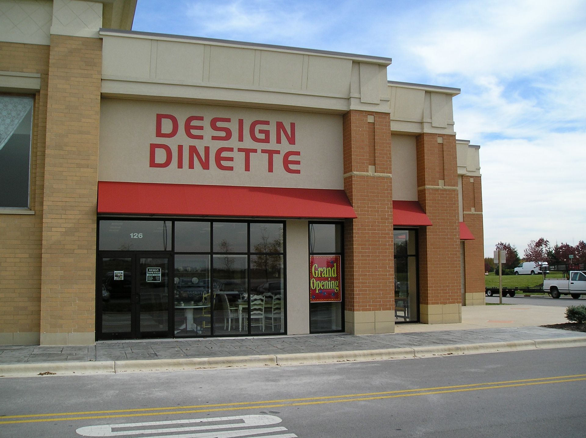 Storefront with red awning and sign reading “DESIGN DINETTE” in a strip mall.