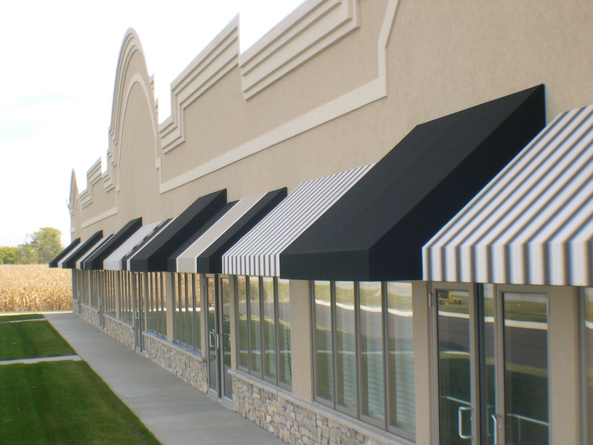 Storefront with black-and-white striped awnings along a beige building exterior