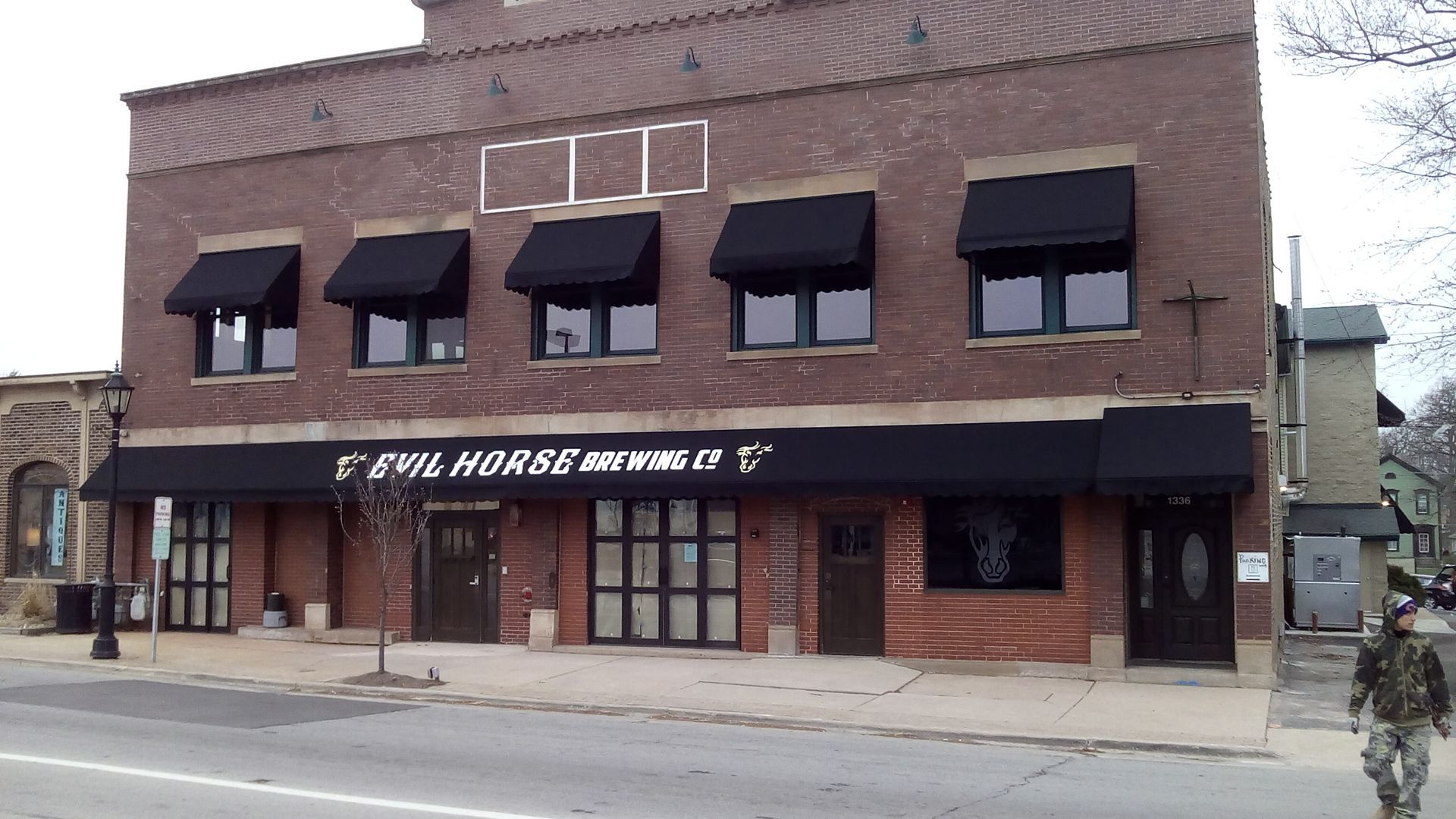 Brick storefront with black awnings and a sign reading “The Horseshoe Bar & Grill” on a street corner