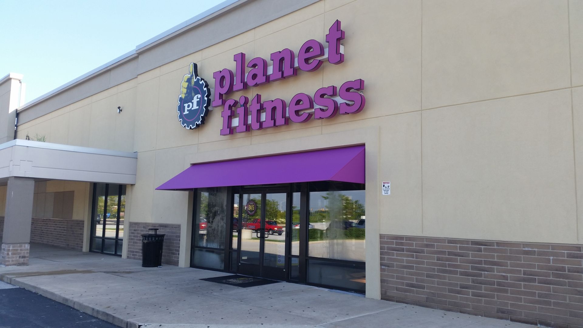 Planet Fitness storefront with purple awning and sign on a beige building