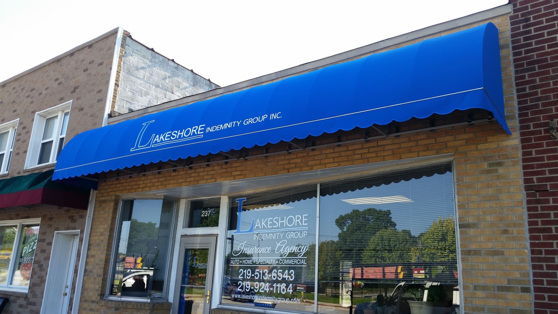 Storefront with bright blue awning and large front windows on a brick building