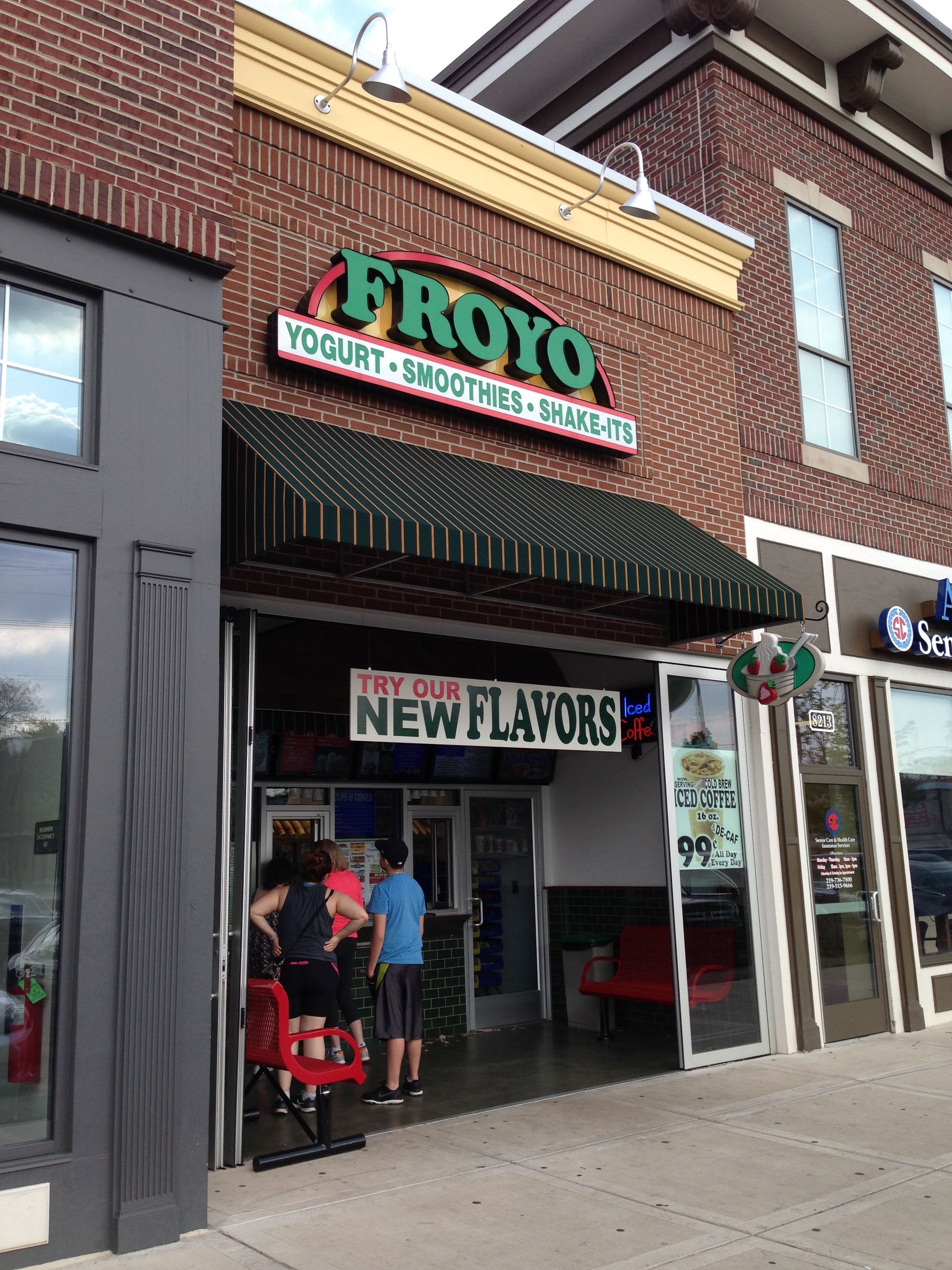 Froyo frozen yogurt shop storefront with green awning and “New Flavors” sign