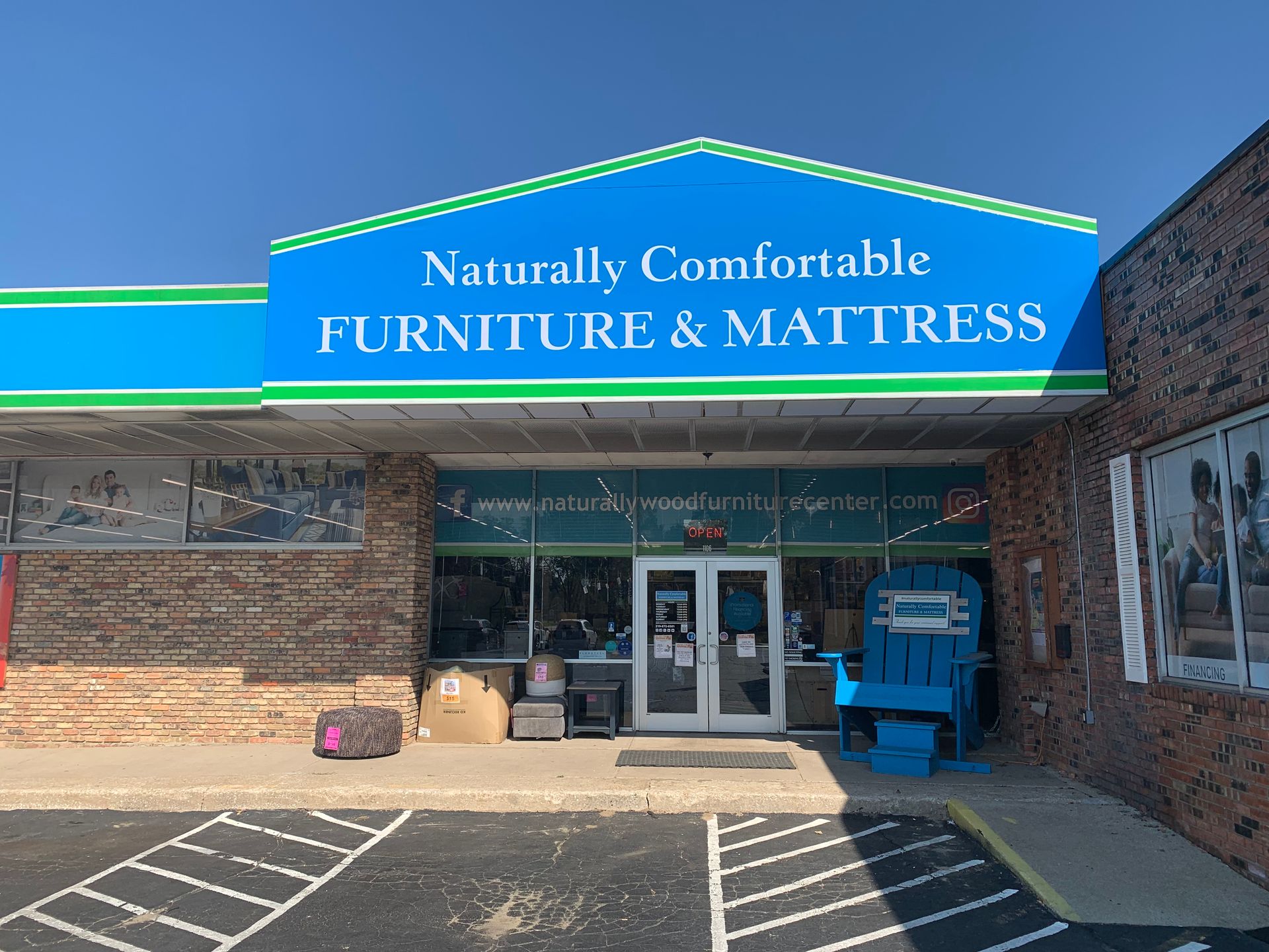 Storefront with blue awning reading “Naturally Comfortable Furniture & Mattress” and brick exterior