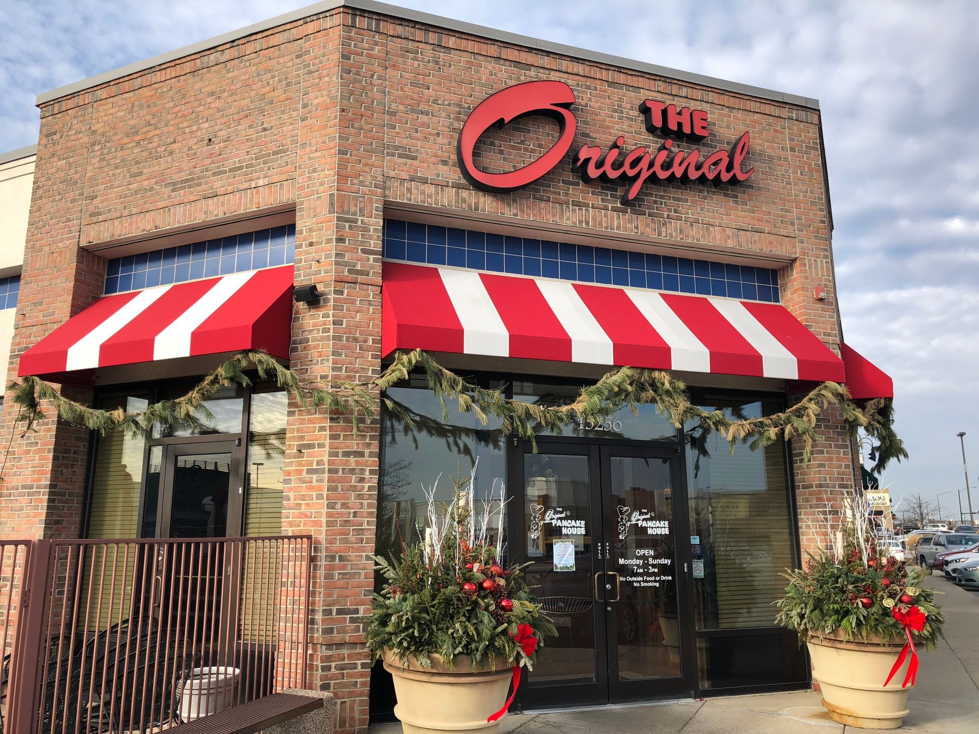 Brick storefront with red-and-white awnings and “The Original” sign, flowers by the entrance