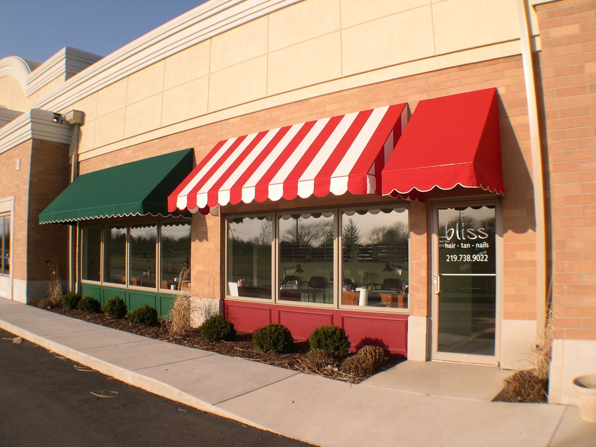 Striped red-and-white awning over storefront with green awning beside it in a shopping center