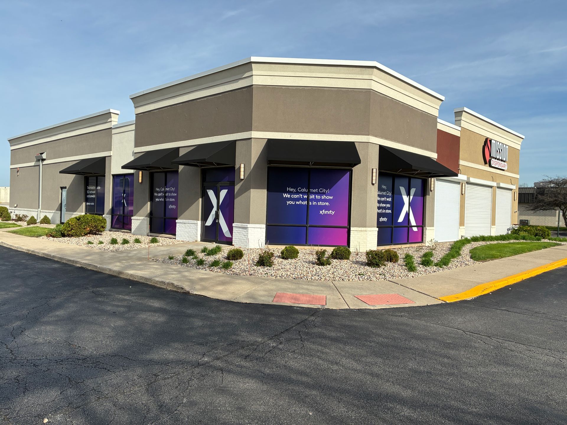 Corner view of a retail building with purple window graphics and a drive-thru lane