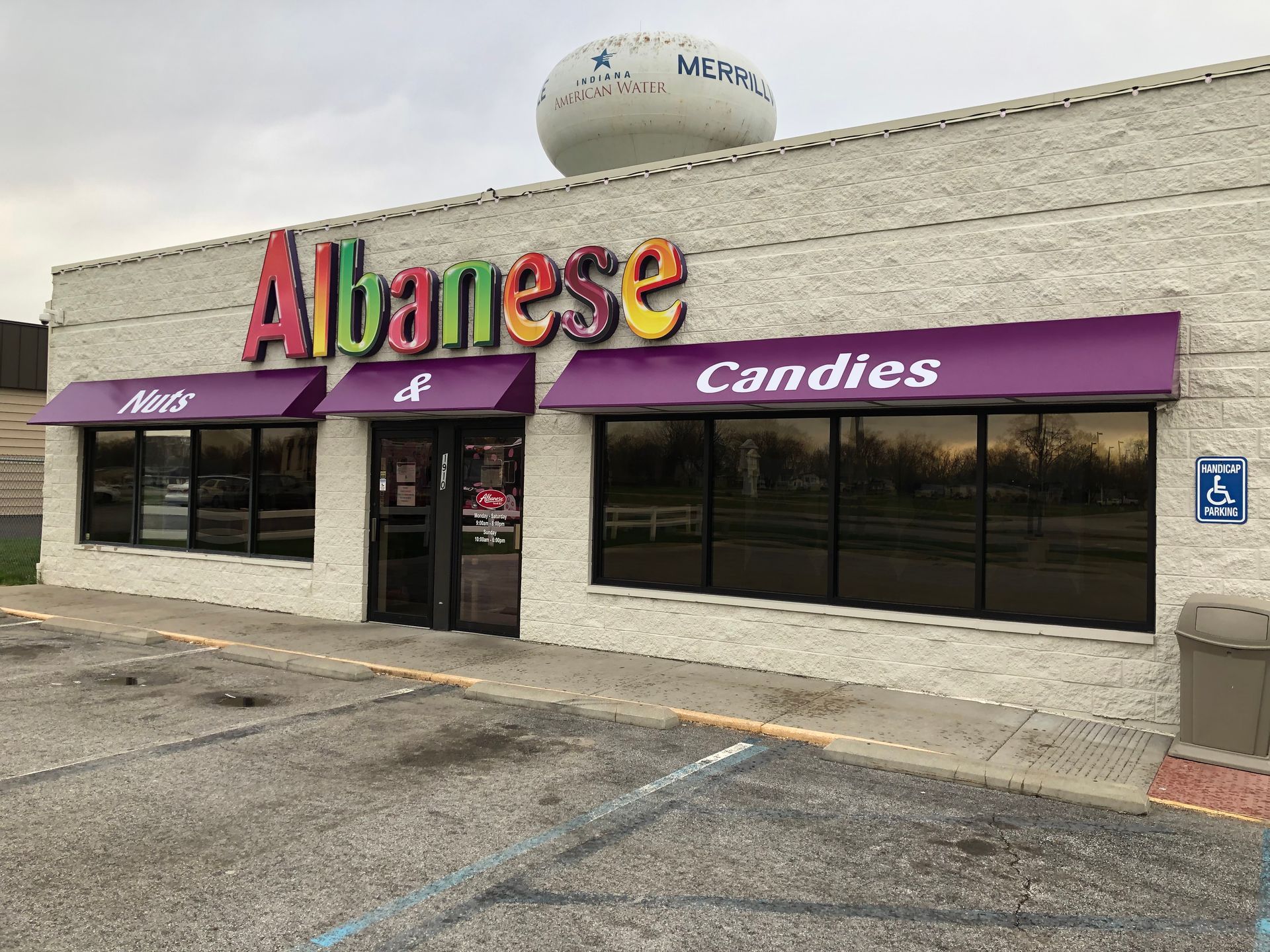 Albanese Candies storefront with purple awning and large colorful sign on a cloudy day