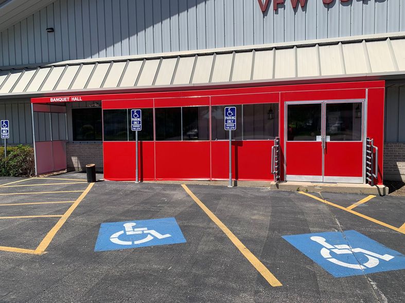 Red storefront entrance with accessible parking spaces marked in blue and yellow lines in front
