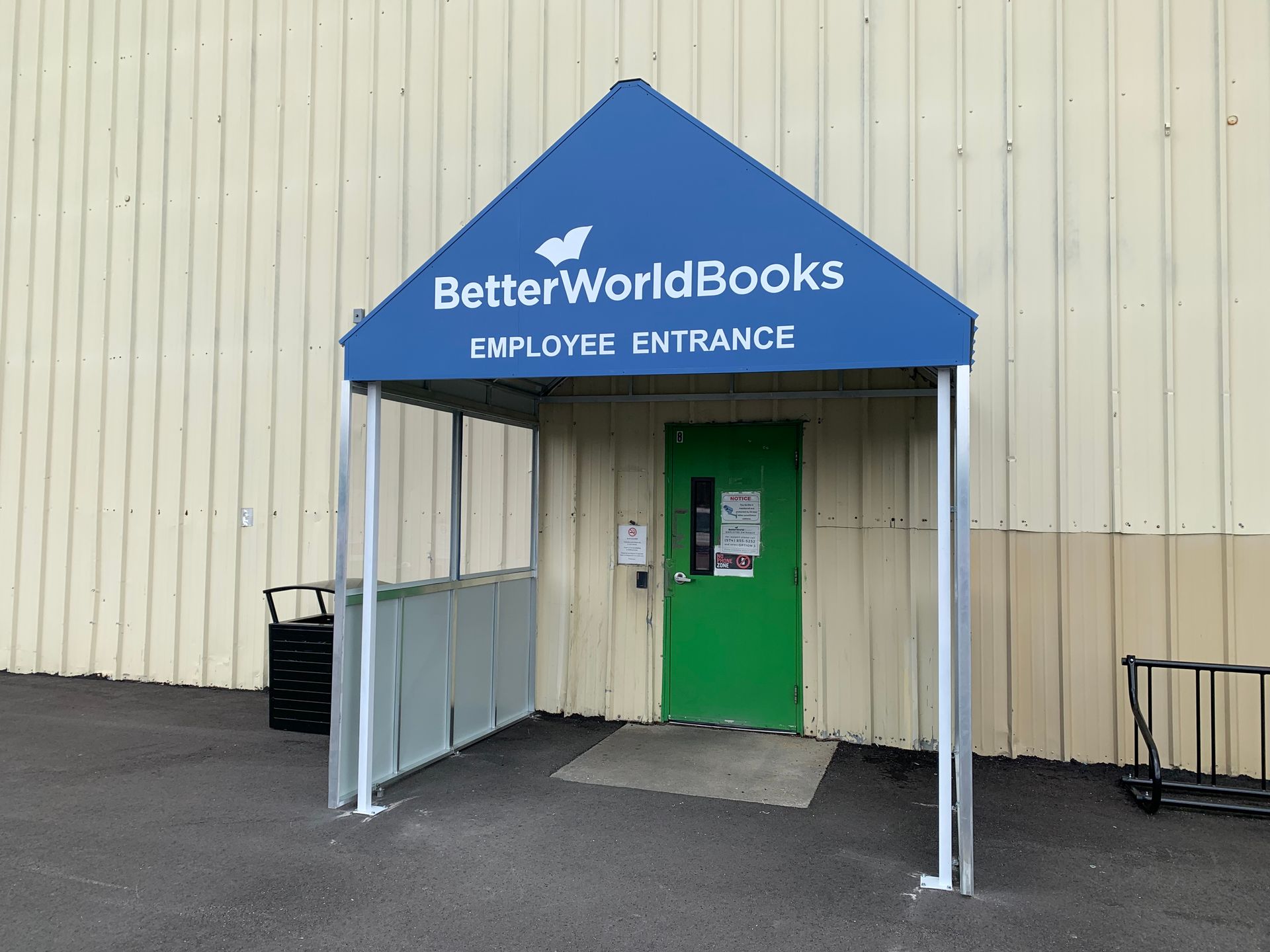BetterWorldBooks employee entrance with blue canopy and green door on beige building