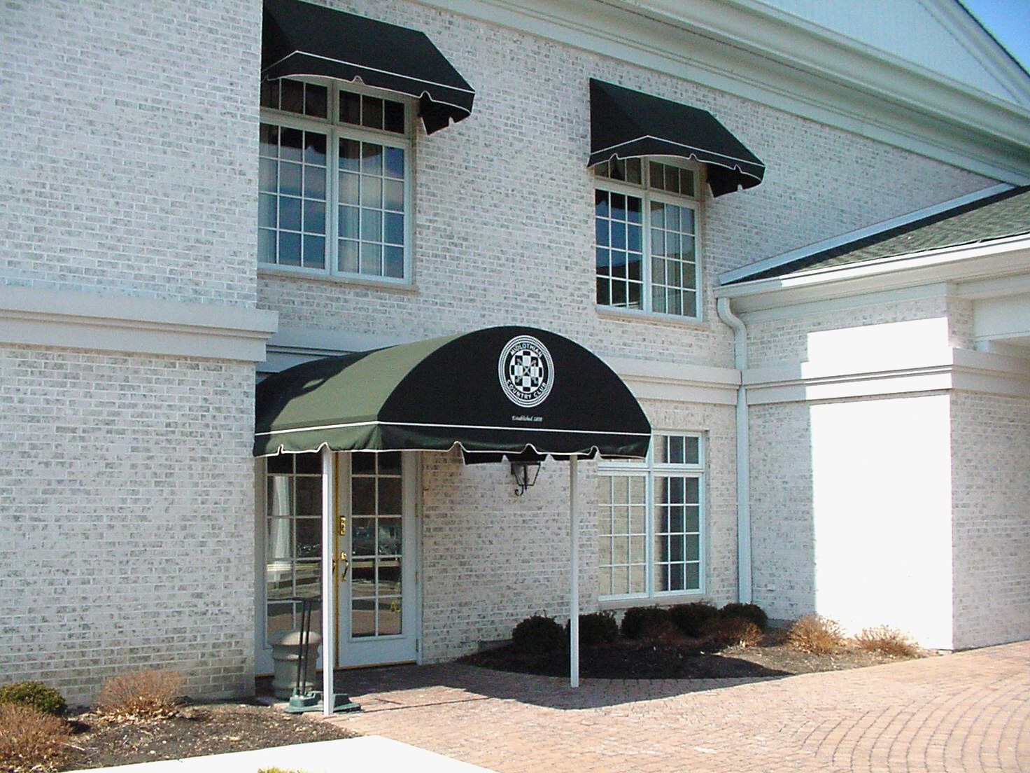 White brick building entrance with black awning and windows above the doorway