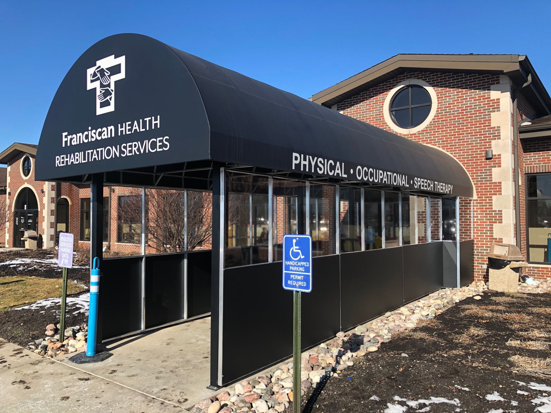 Exterior of Christian Health Rehabilitation Services building with black awning and wheelchair parking sign