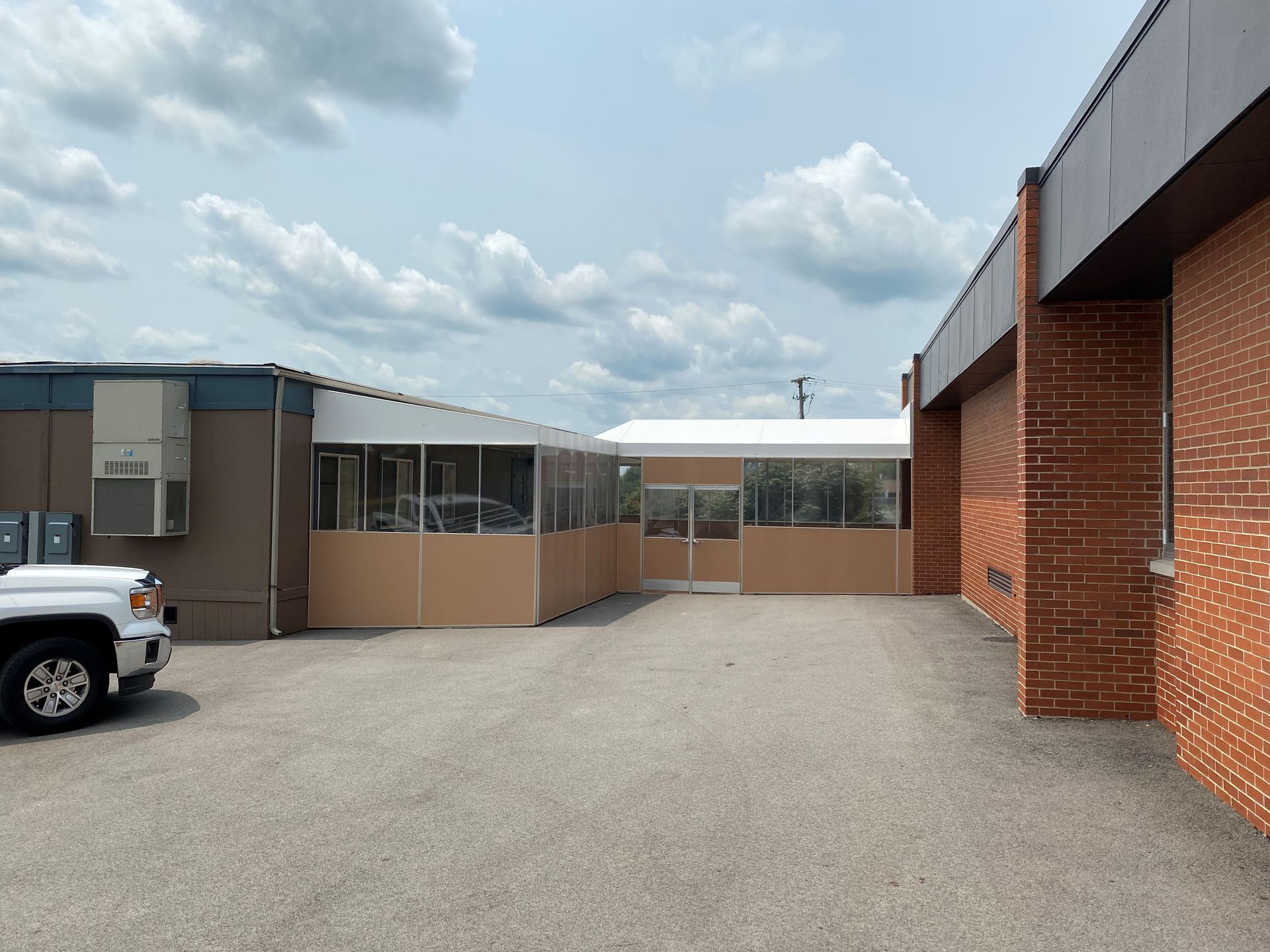 Courtyard between brick buildings with a parked white truck and cloudy sky overhead