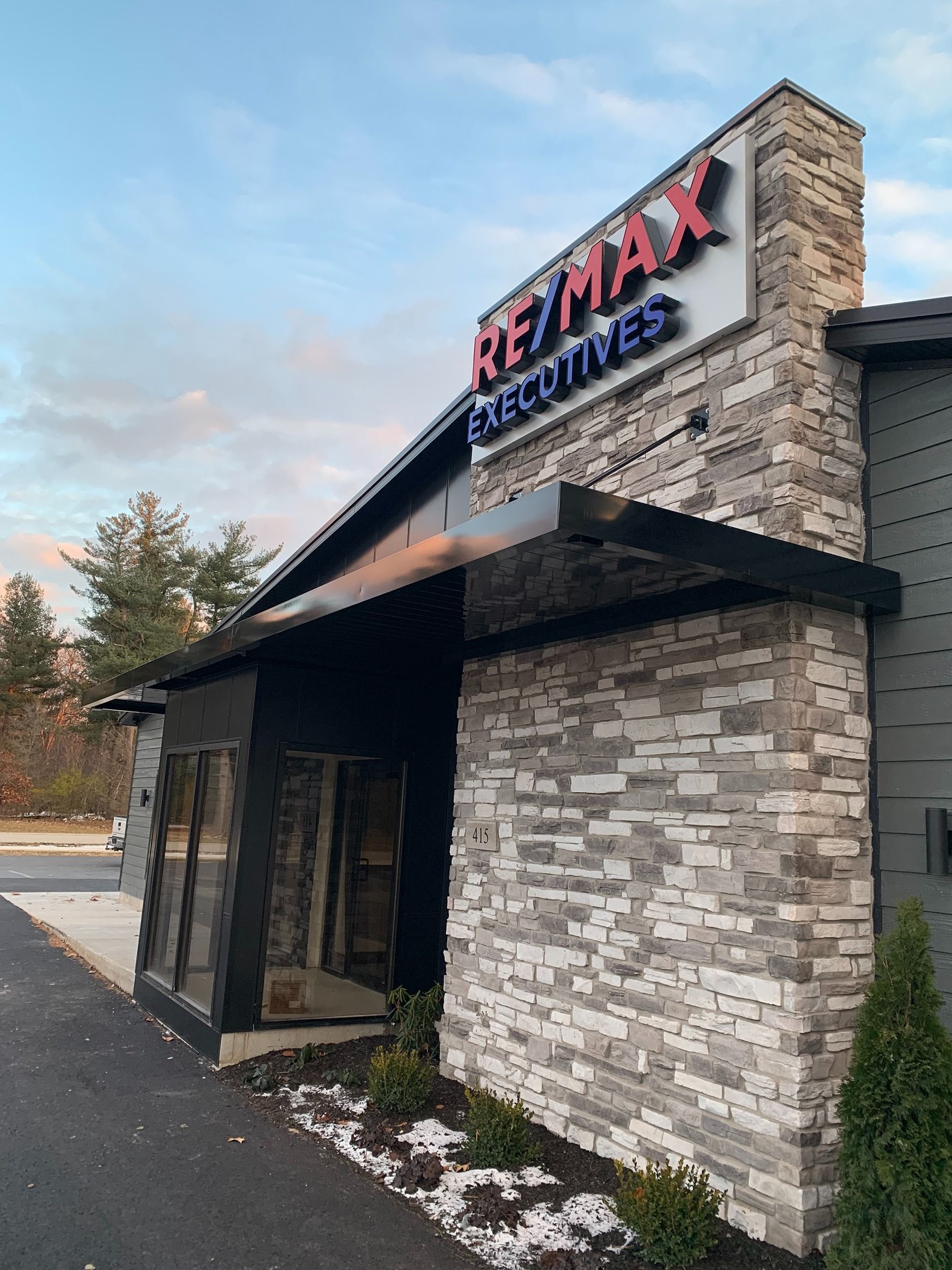 RE/MAX real estate office exterior with stone facade and covered entrance at dusk
