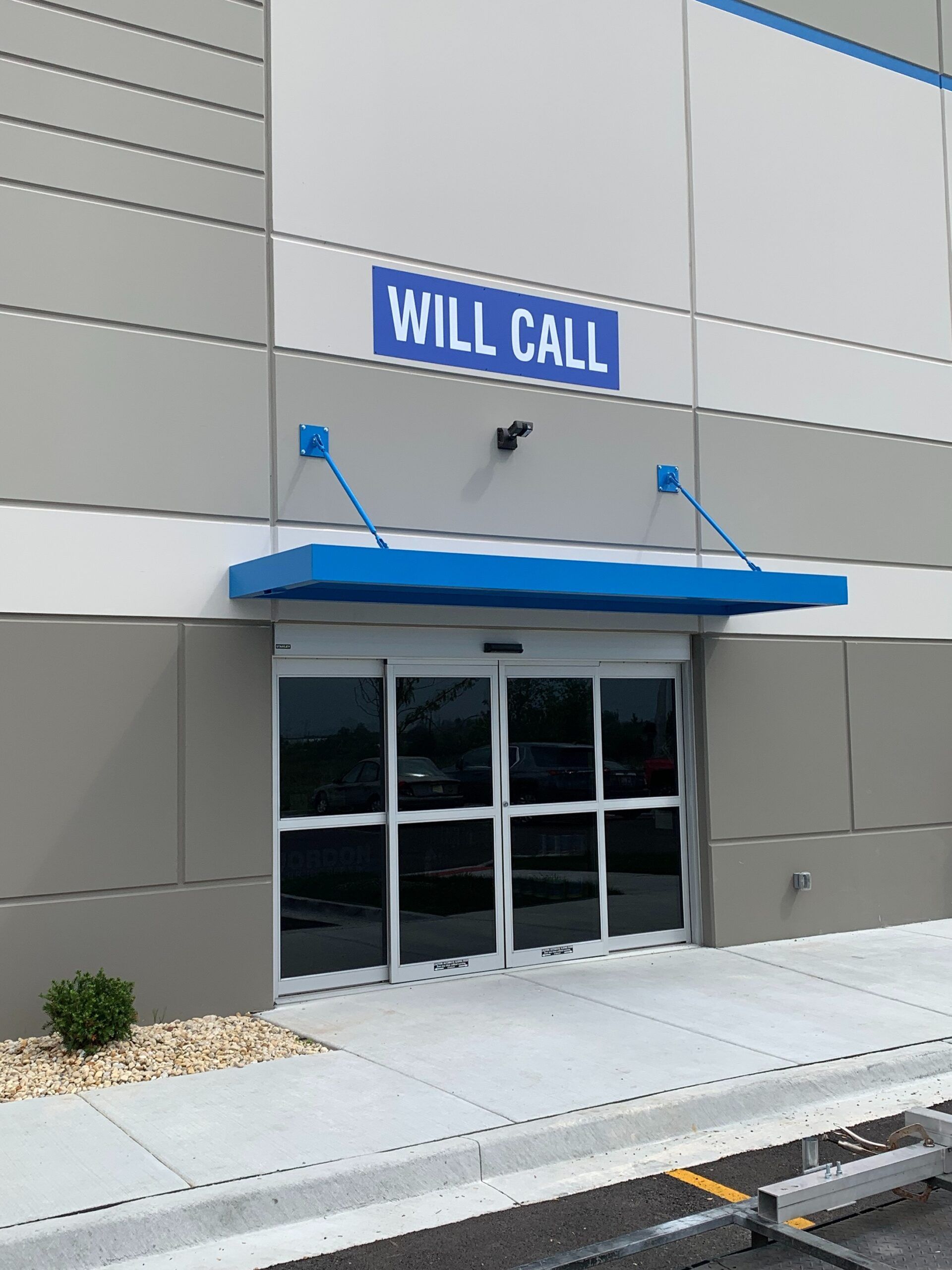 Storefront entrance with blue awning and “WILL CALL” sign above glass doors