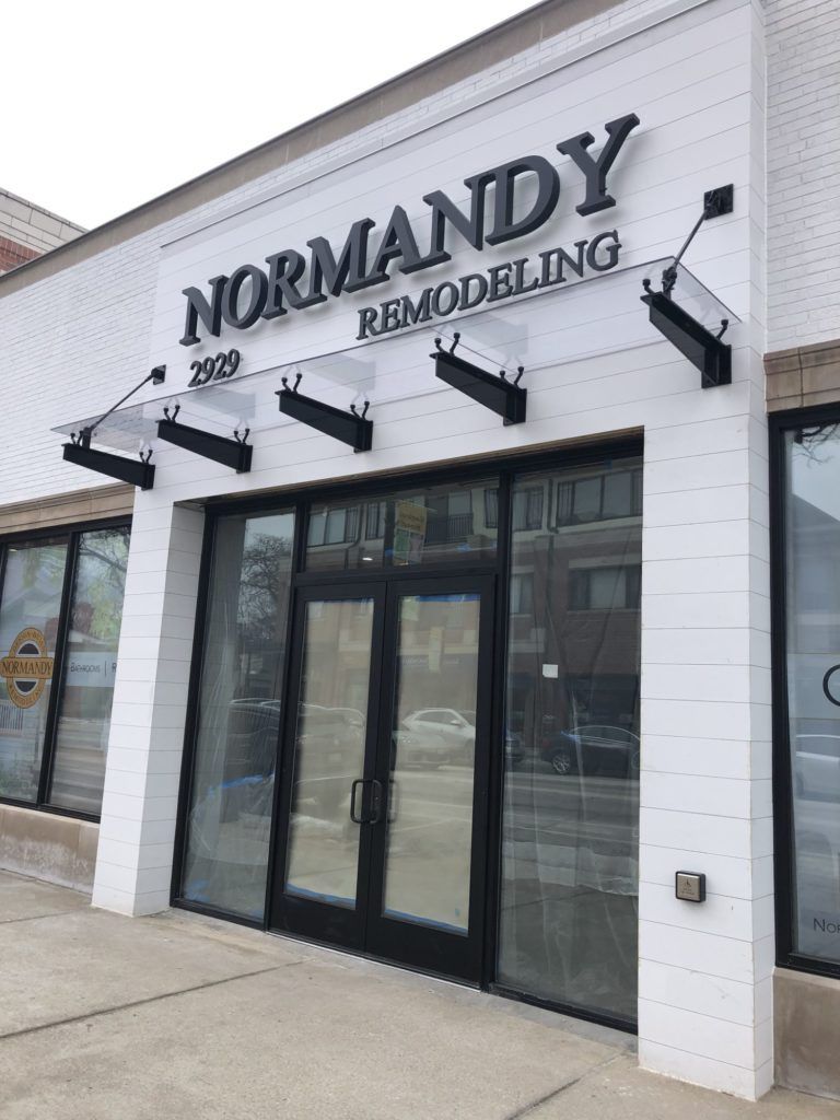 Storefront for Normandy Remodeling with black-framed glass doors and white brick exterior