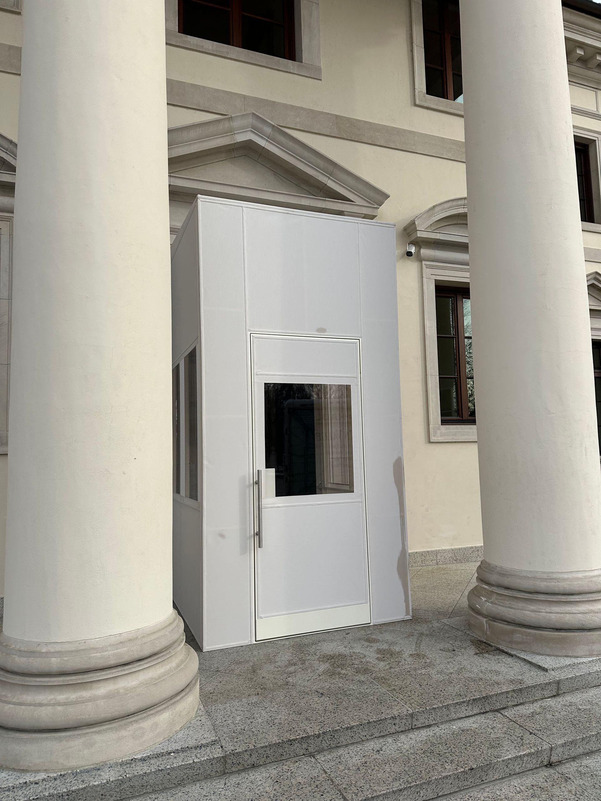 White temporary booth between large columns outside a building