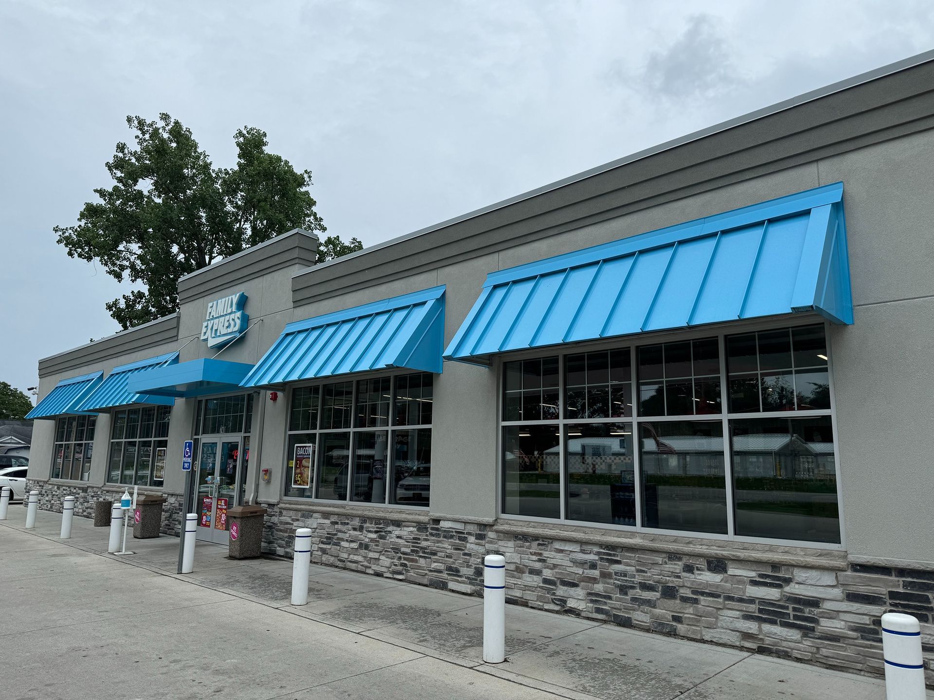 Storefront with bright blue awnings and large windows on a cloudy day