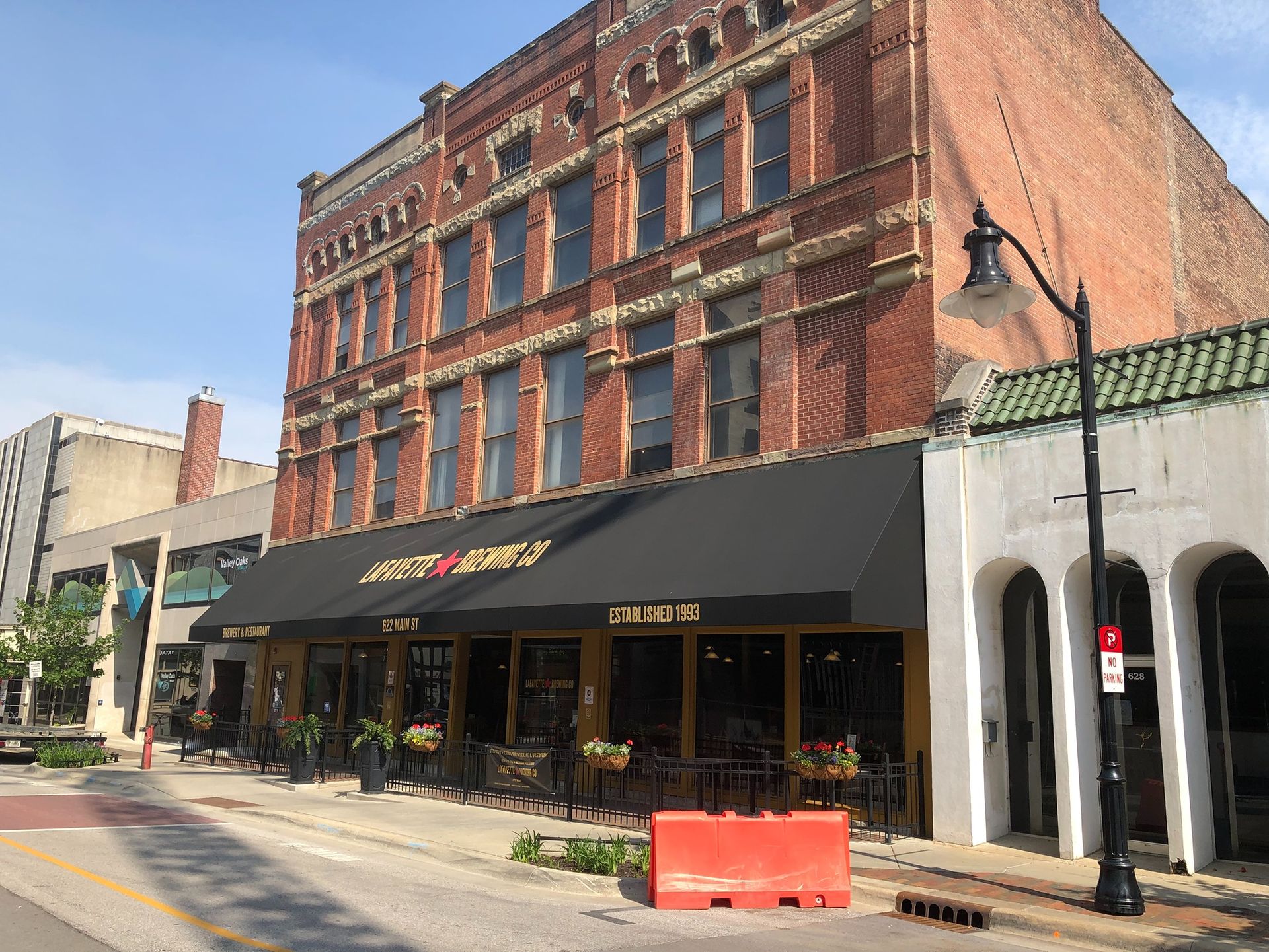 Brick storefront with black awning and outdoor seating on a sunny city street