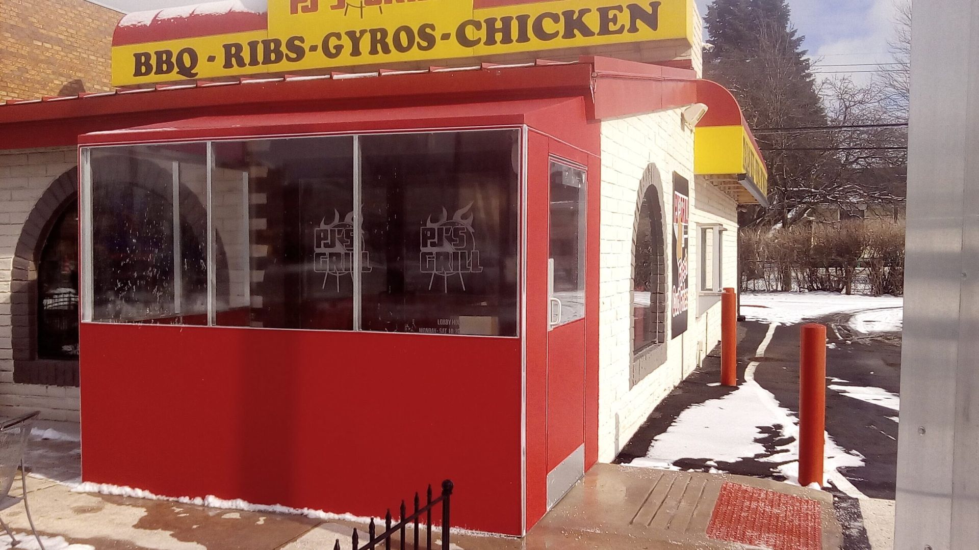 Red food stand with yellow sign reading “BBQ-RIBS-GYROS-CHICKEN” in a snowy outdoor setting