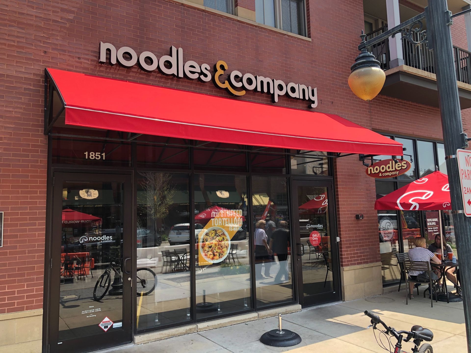 Noodles & Company storefront with red awning and outdoor patio seating