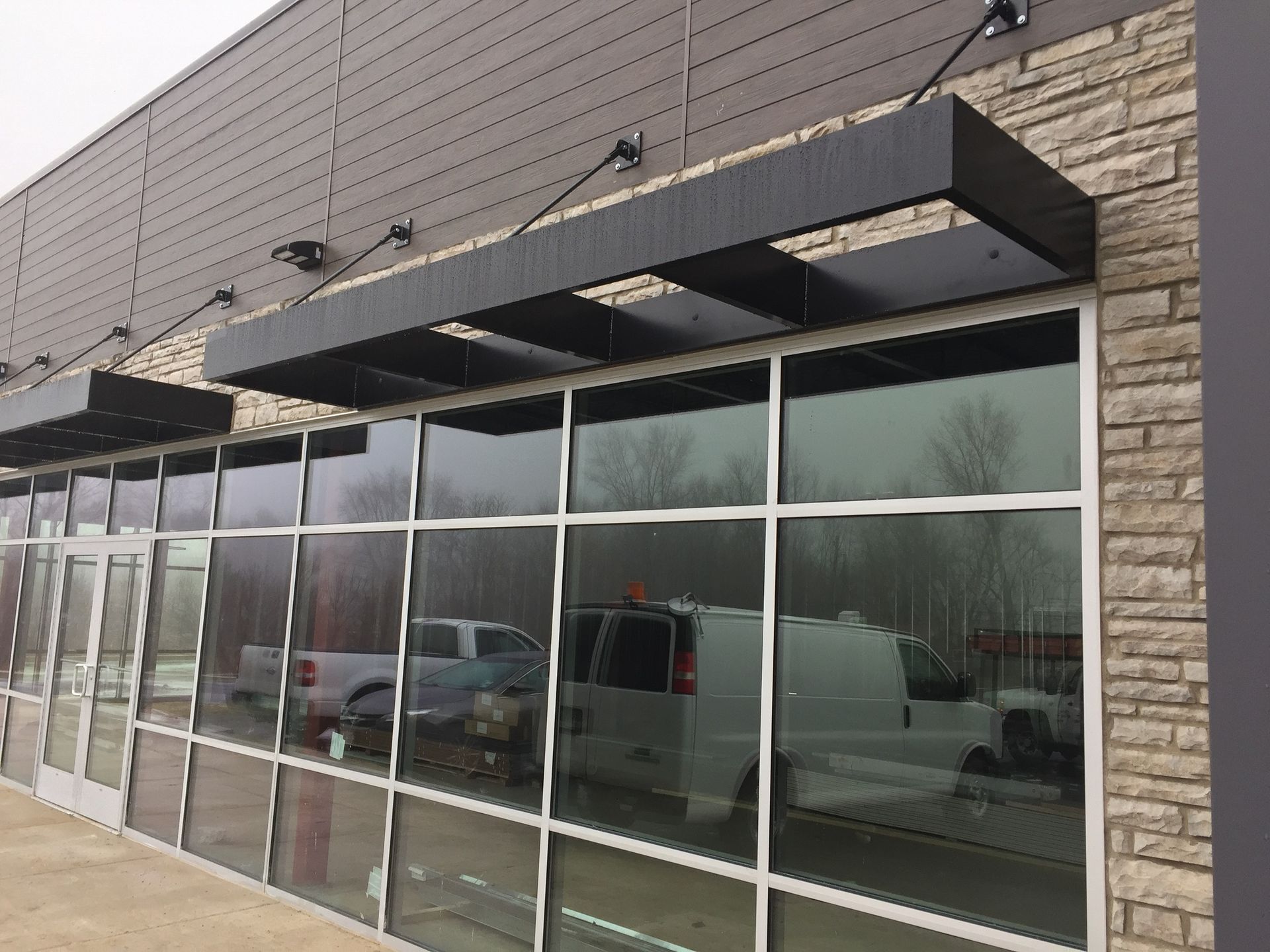 Storefront with large reflective windows and black awnings on a brick building