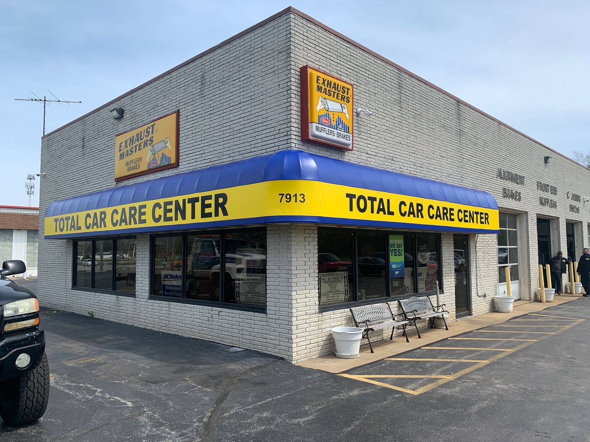 Total Car Care Center storefront with yellow awnings on a brick corner building.