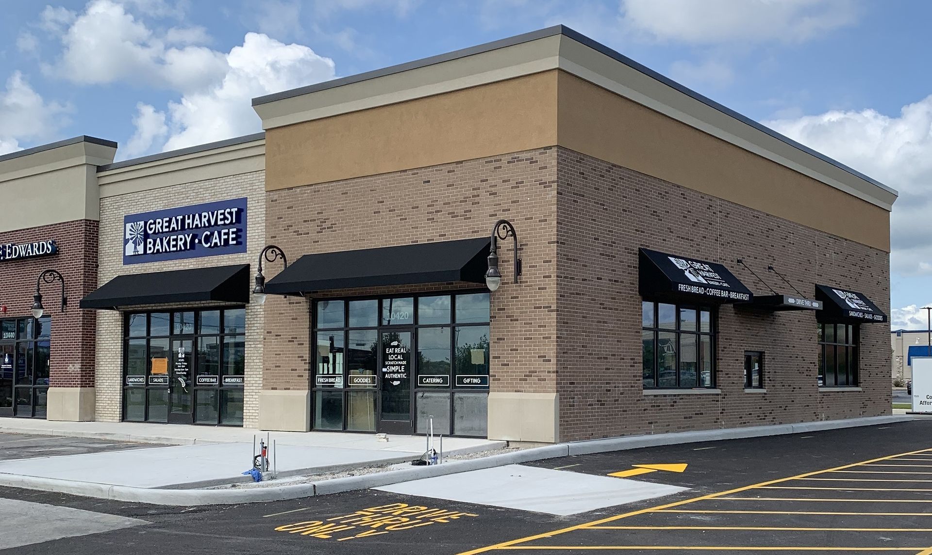 Corner storefront in a shopping plaza with brick walls, black awnings, and a blue sign above the entrance.
