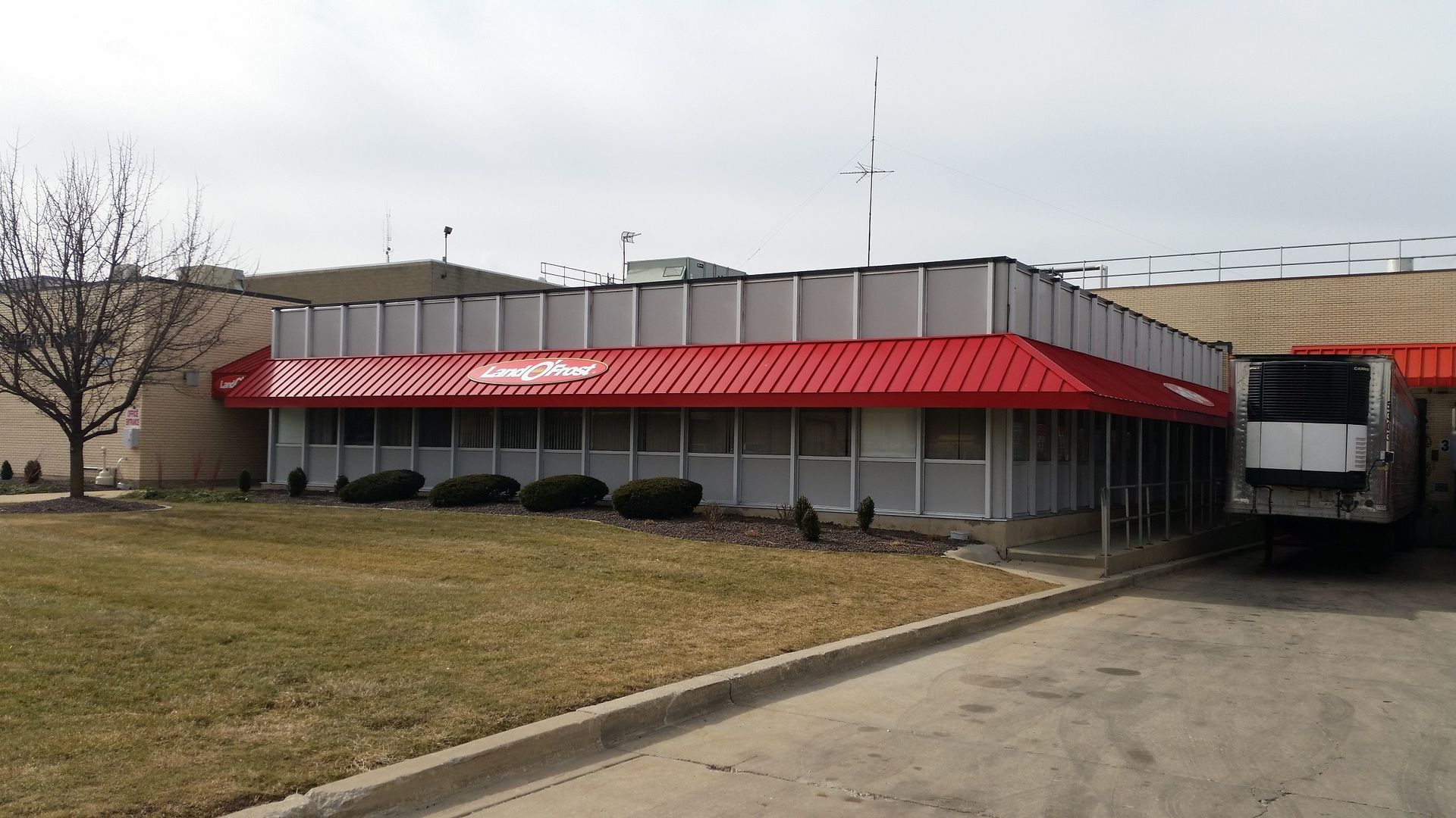 Industrial building with a red awning, bare trees, and a loading dock on an overcast day