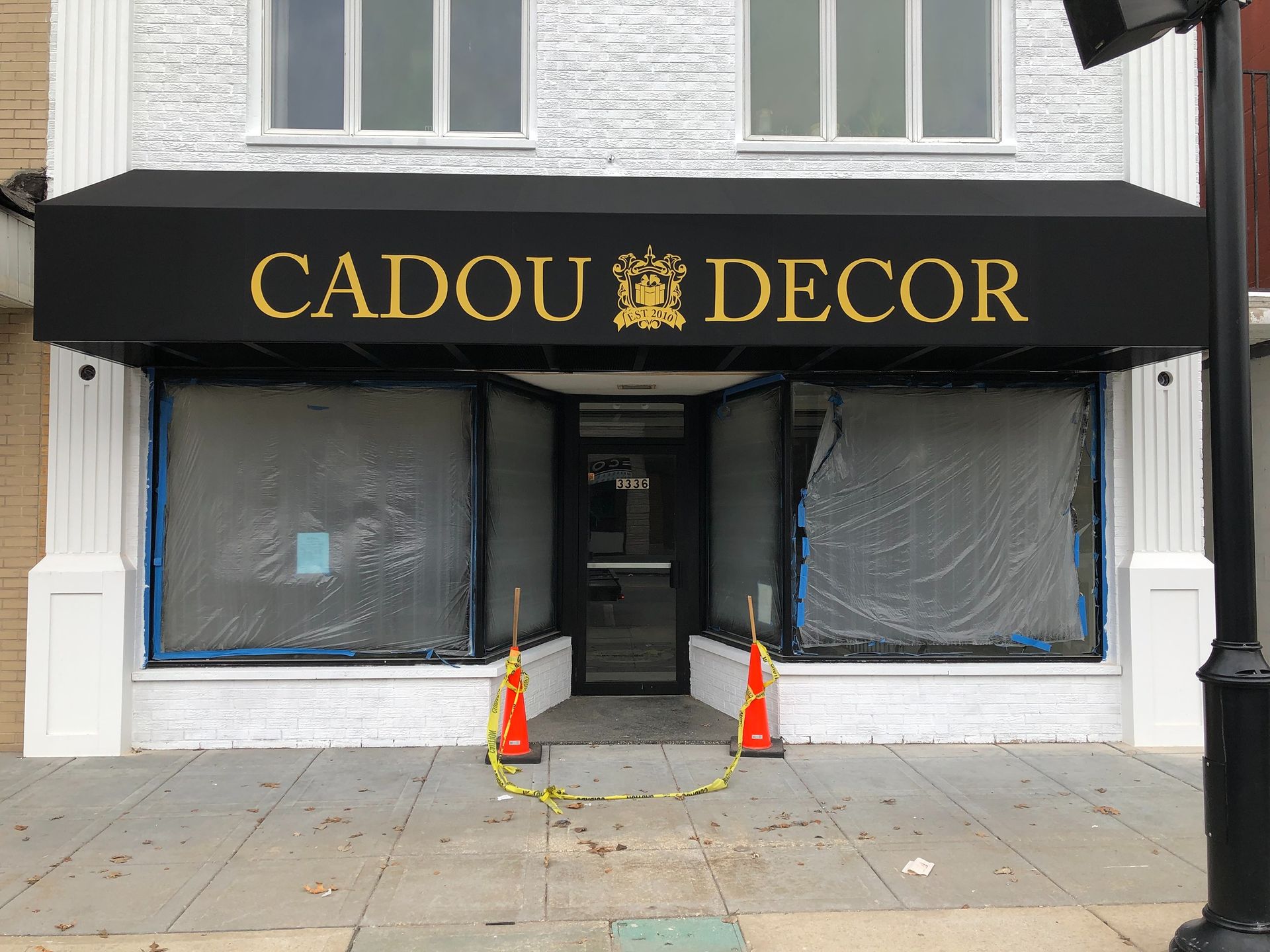 Closed CADOU DECOR storefront with boarded windows and orange traffic cones on the sidewalk