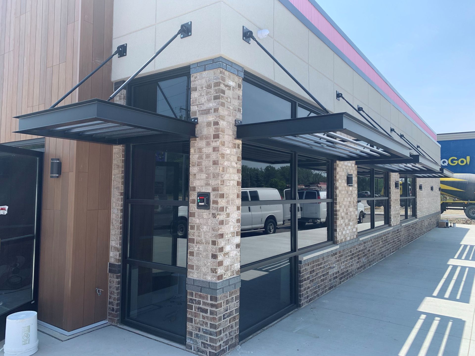 Corner storefront with black awnings and brick accents on a city street.