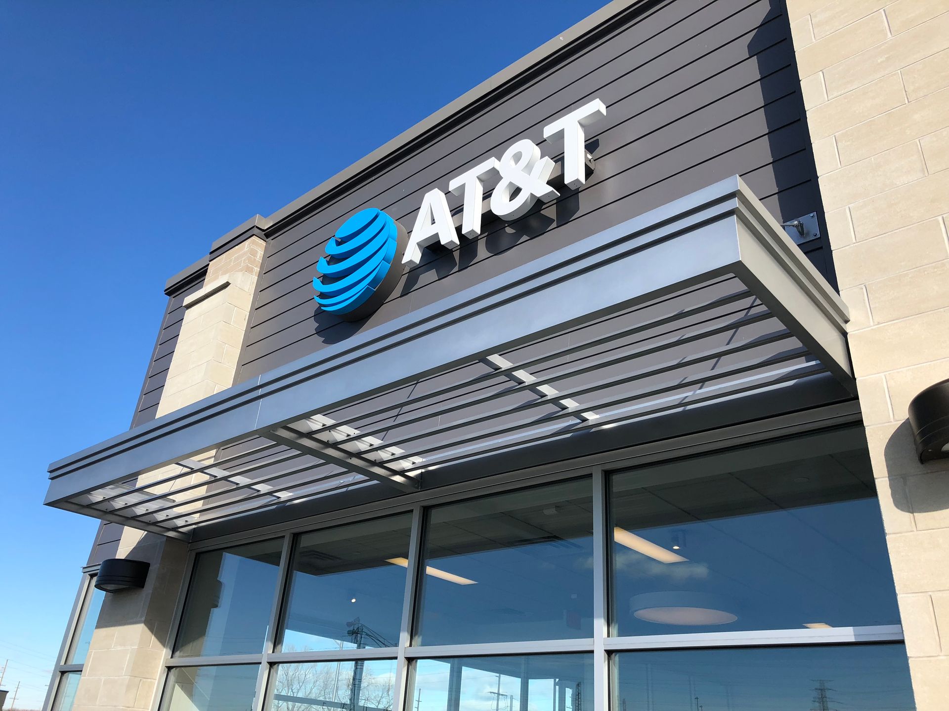 AT&T storefront with blue logo and glass awning on a sunny day