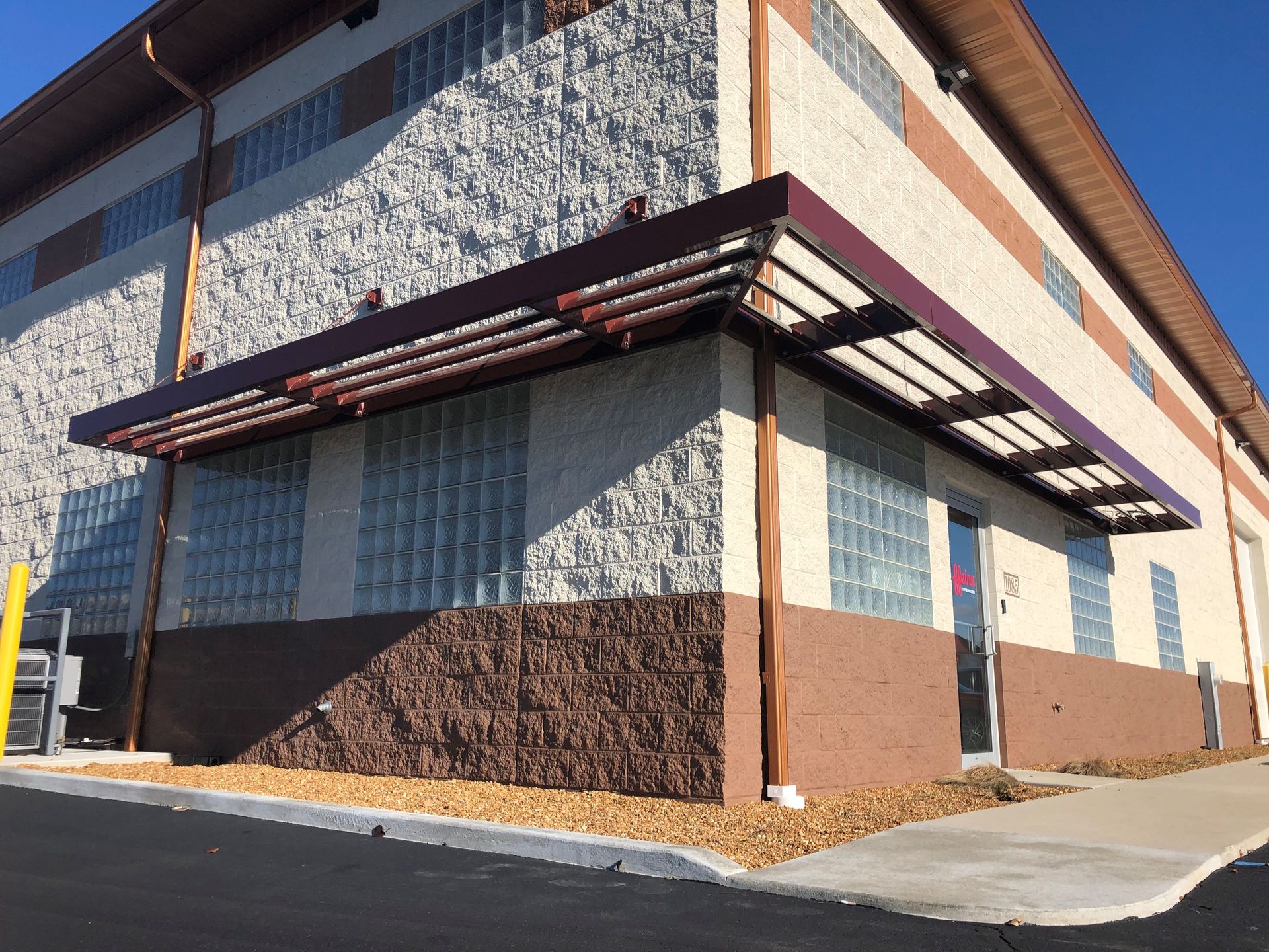 Modern building exterior with patterned walls, brown awnings, and a concrete walkway.