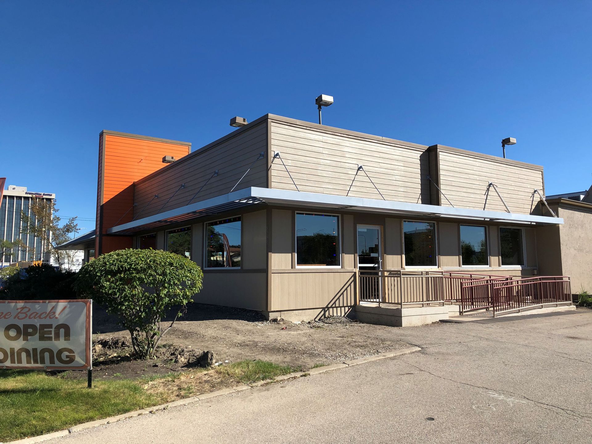Small roadside restaurant with patio seating and an “OPEN DINING” sign on a sunny day