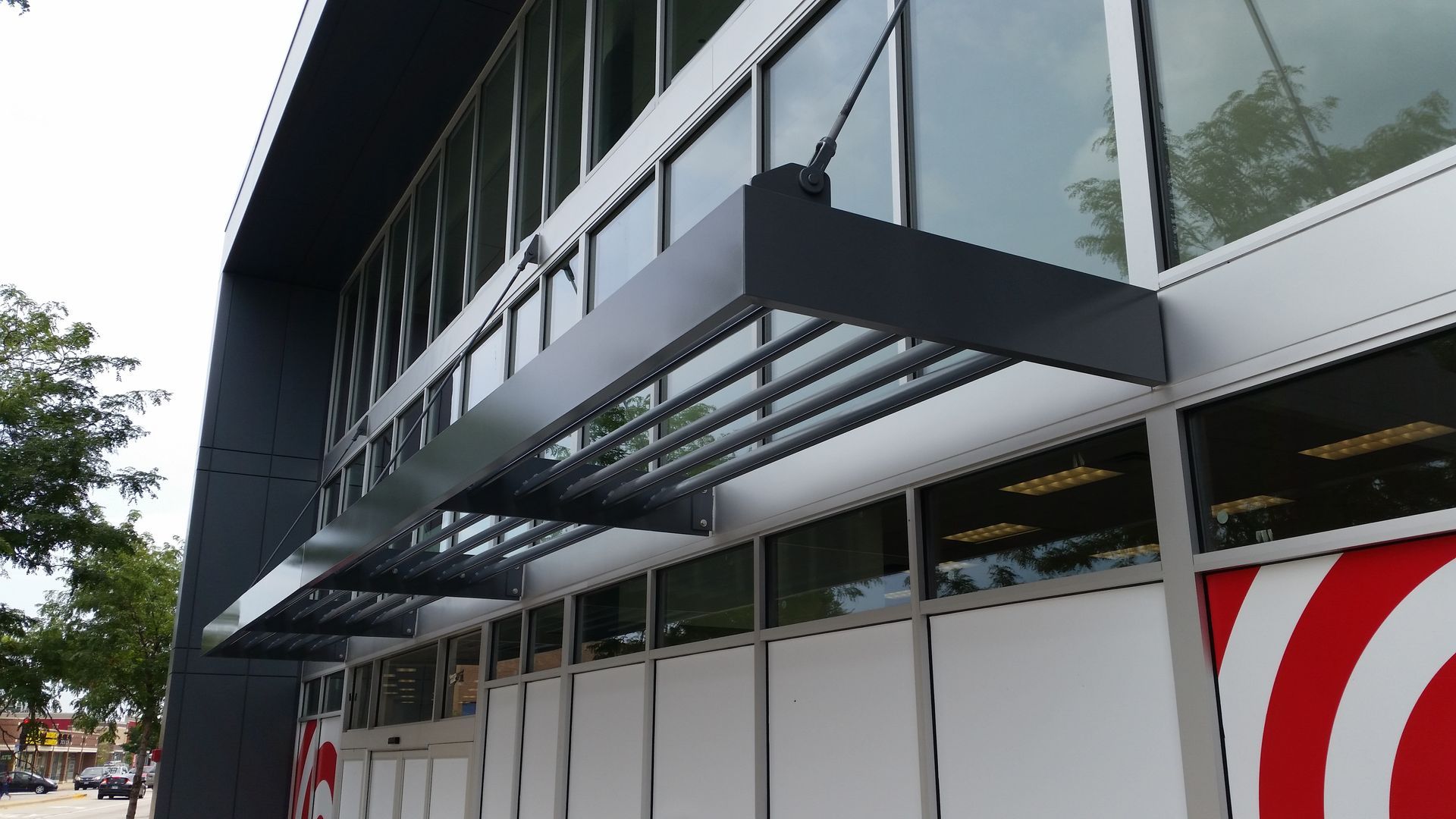 Modern building facade with black awnings and large glass windows on a city street