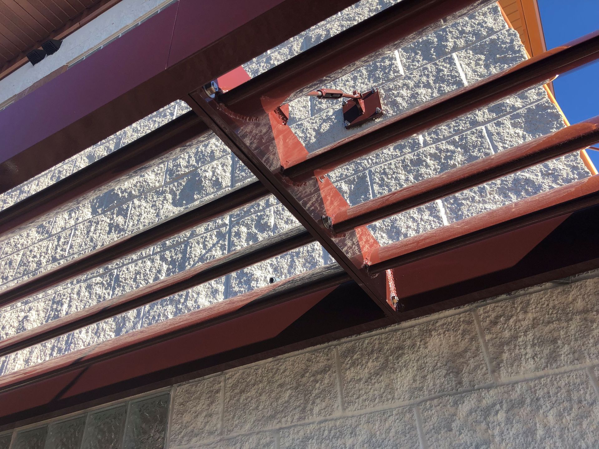 Red metal railing above a gray concrete wall against a blue sky