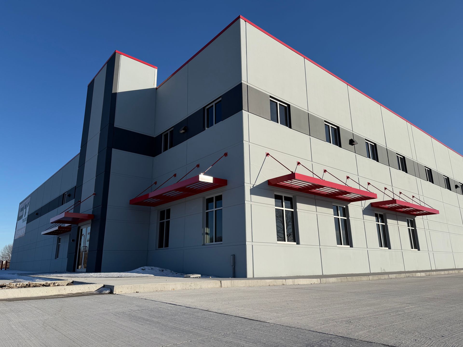 Modern gray industrial building with red awnings under a clear blue sky