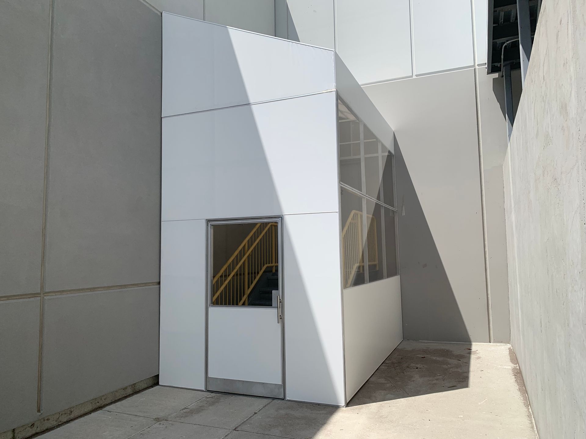 Modern white geometric building with a small door and windows in a narrow alley
