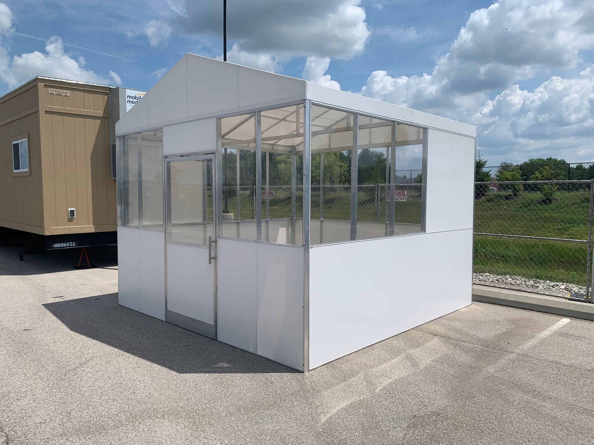 Small white-and-clear plastic shelter on a paved lot under a cloudy sky