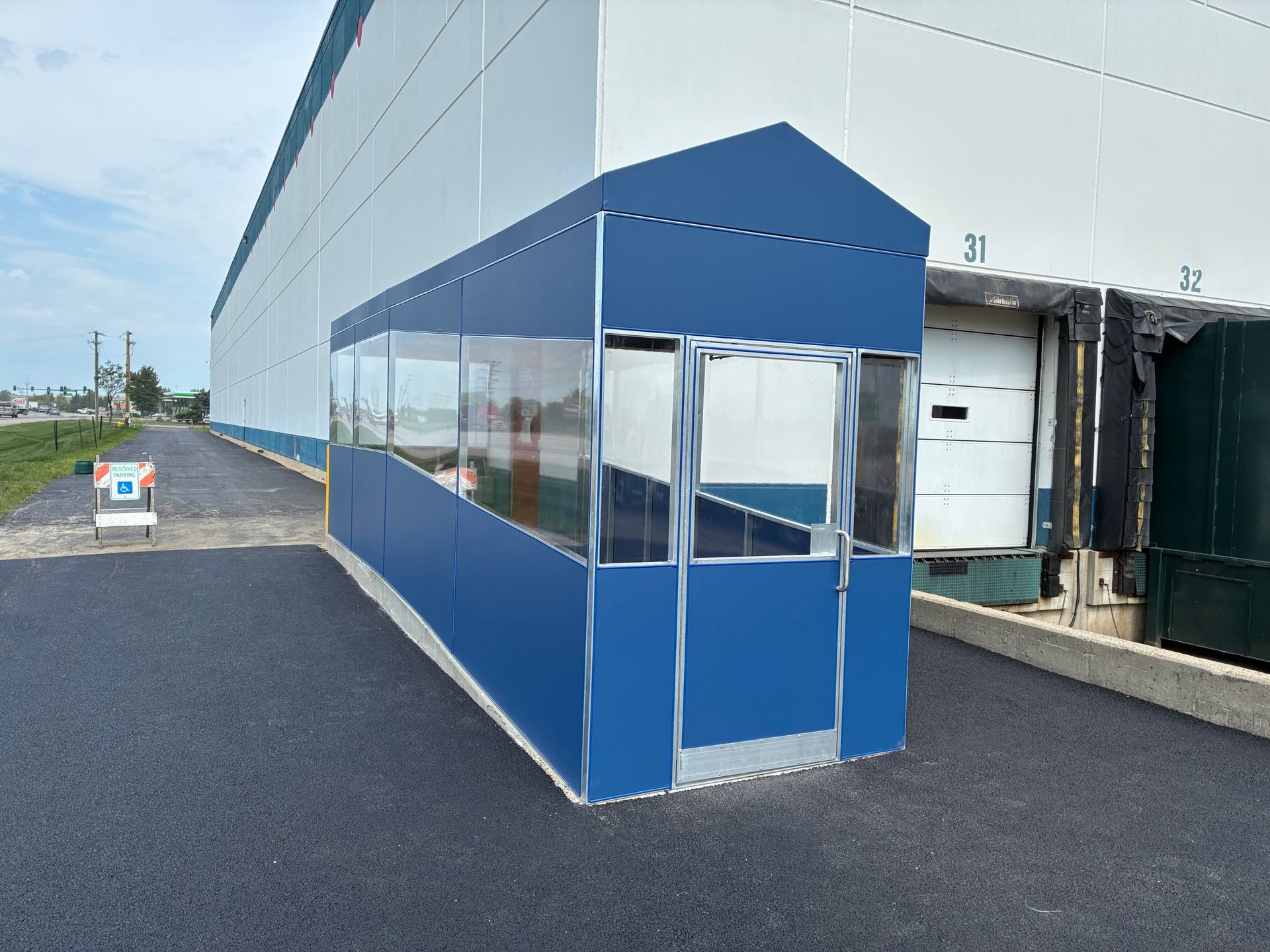 Blue tented walkway beside a gray building on a paved industrial lot