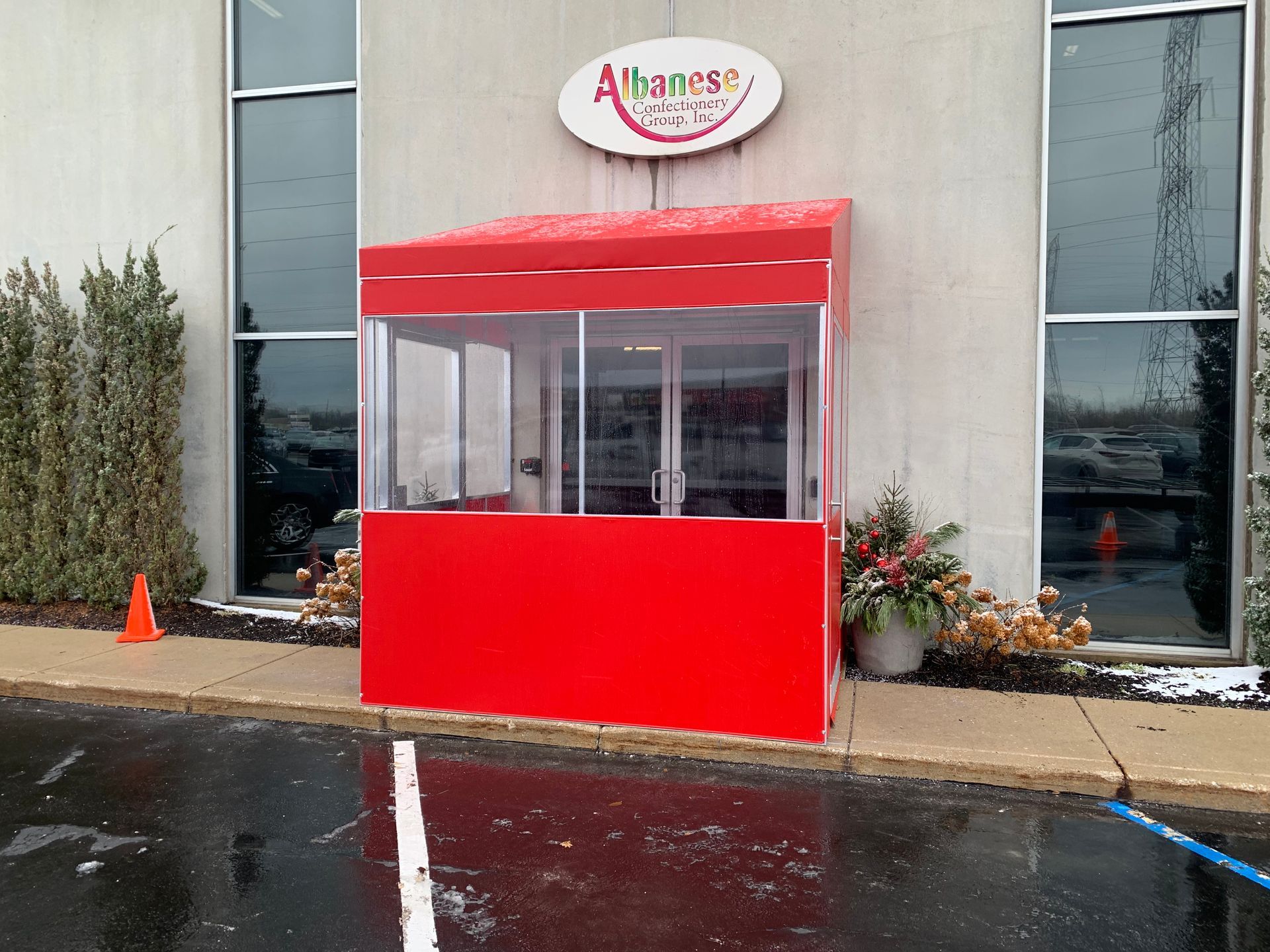 Red kiosk outside a building entrance on a rainy day.