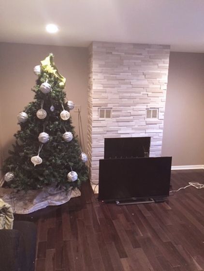 A Christmas tree in a living room next to a fireplace