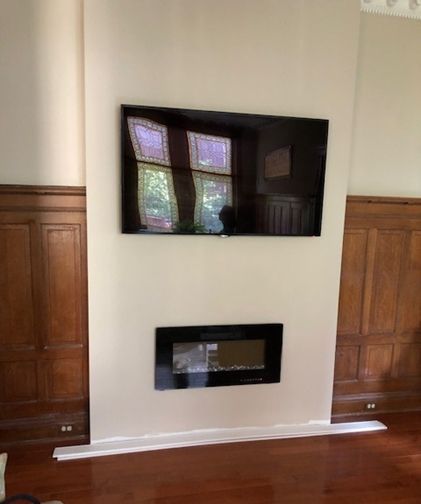 A wall with a fireplace and a flat-screen TV